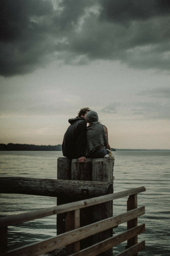 Couple kissing on pier dock pilings by ocean