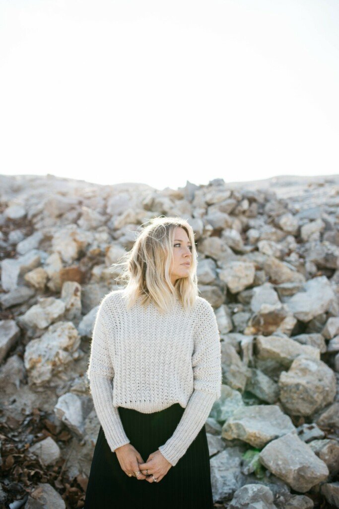 Woman standing at a beach rock wall and staring into middle distance. Photo by Brooke Cagle