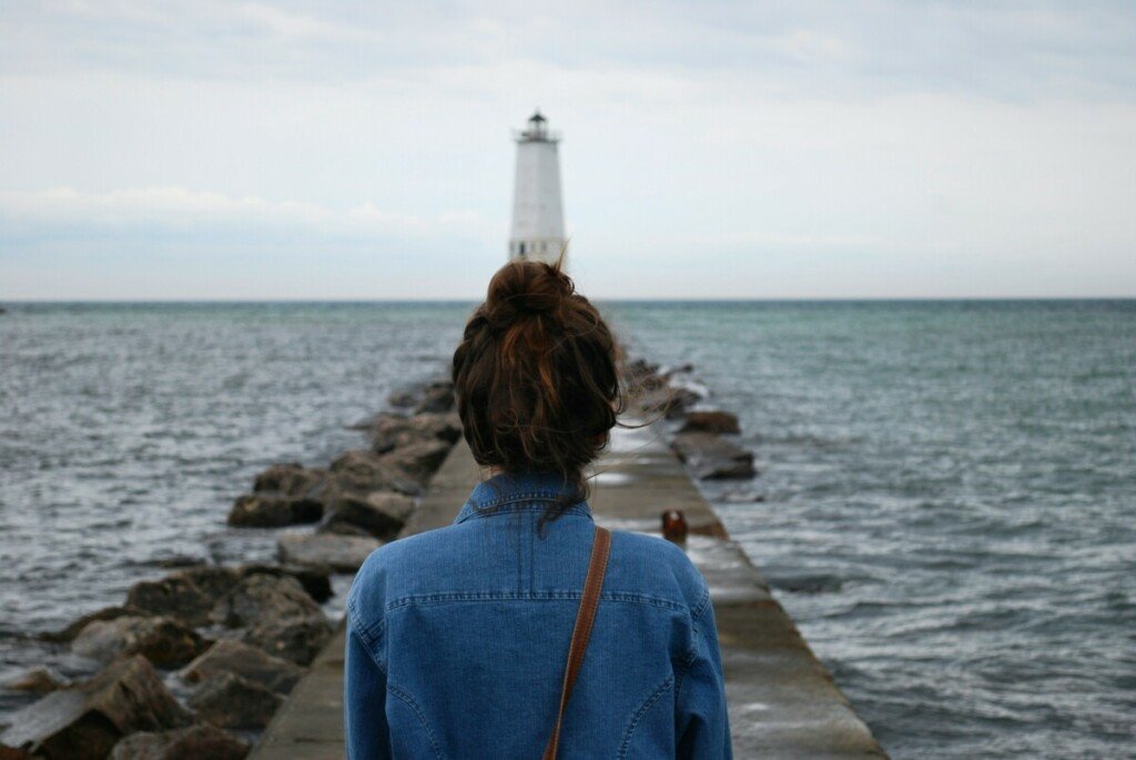 Woman looking at lighthouse on ocean.